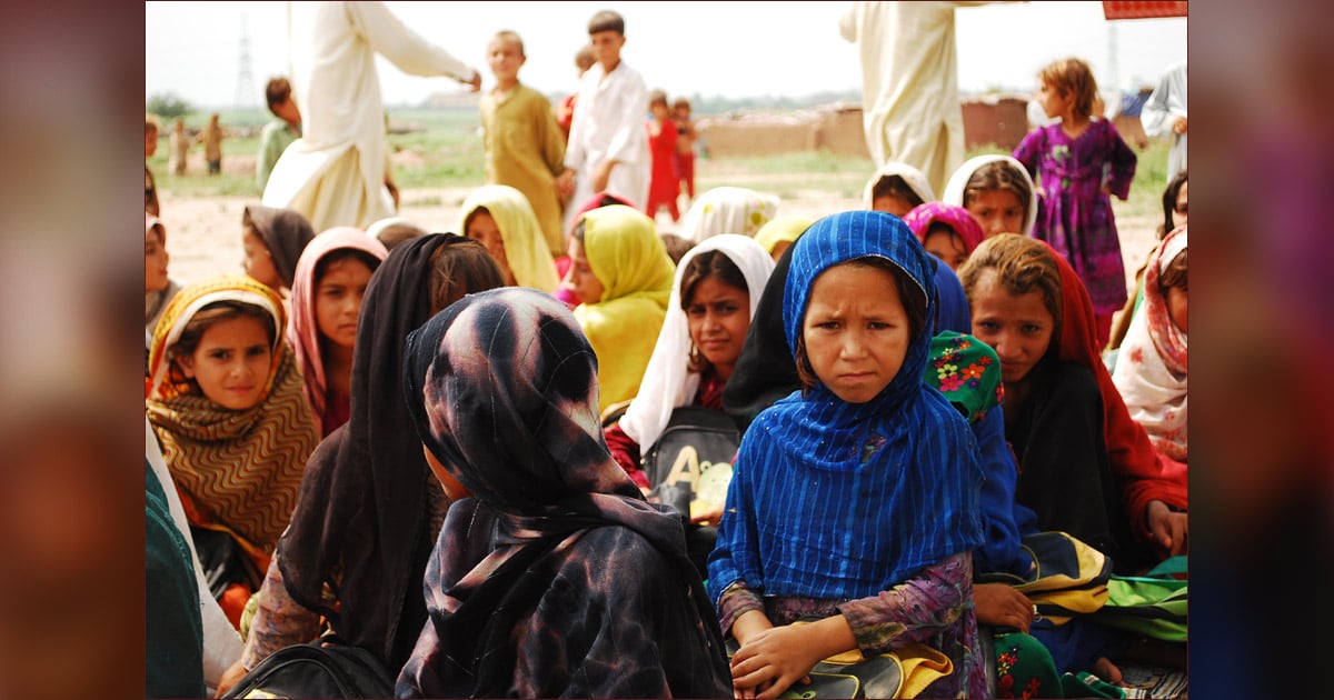 Several children are gathered with a few adults in the background.