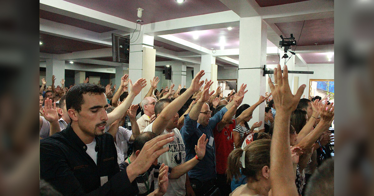 Several people have their hands raised in worship. Several people have their hands raised in worship.