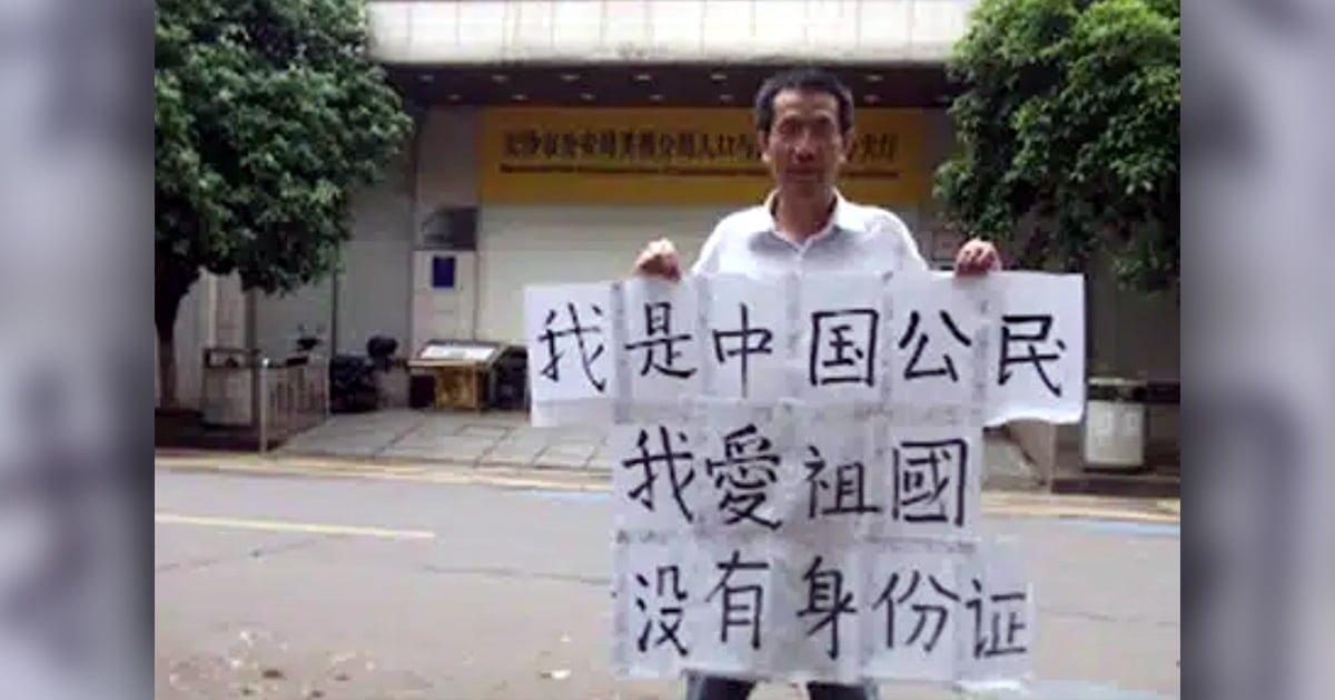 John Cao is holding up a sign with Chinese lettering.