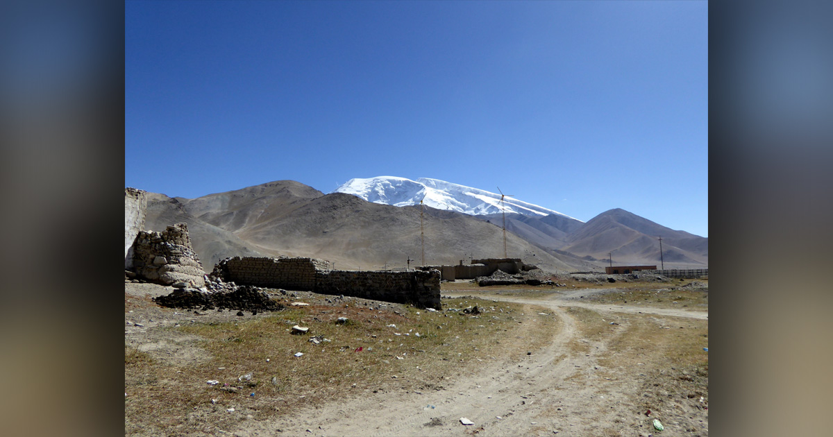Stone buildings on dry terrain; there is a snow-covered mountain in the background. Stone buildings on dry terrain; there is a snow-covered mountain in the background.
