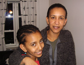 Helen Berhane and her daughter are smiling. Helen has her arm wrapped around her girl.