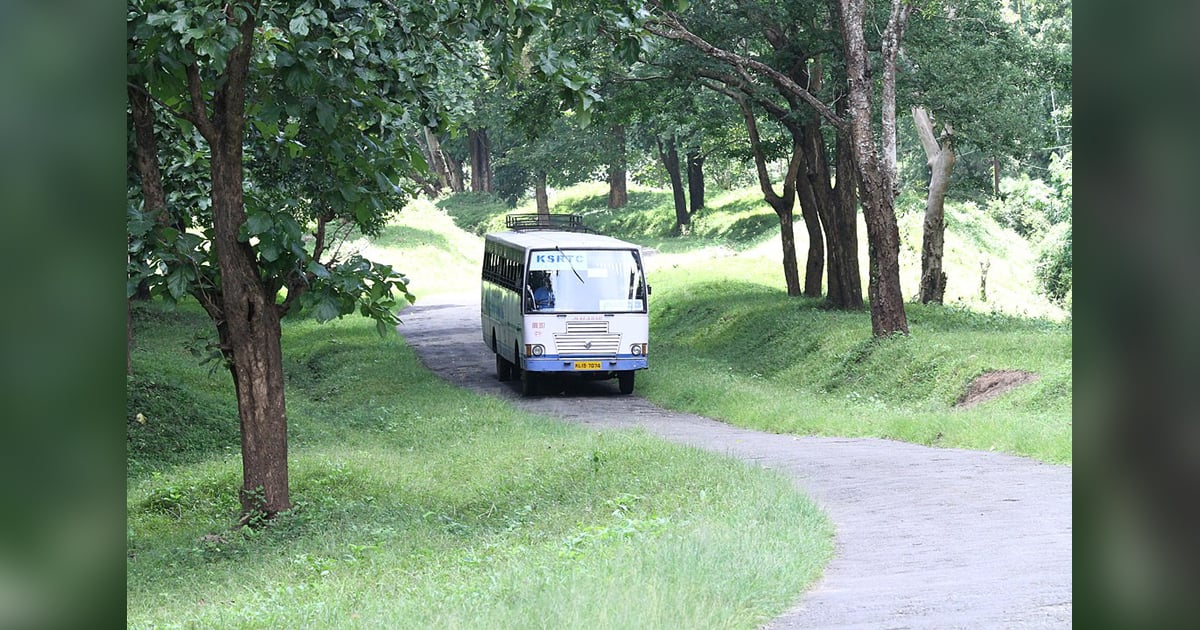 A bus is travelling down a narrow road. A bus is travelling down a narrow road.