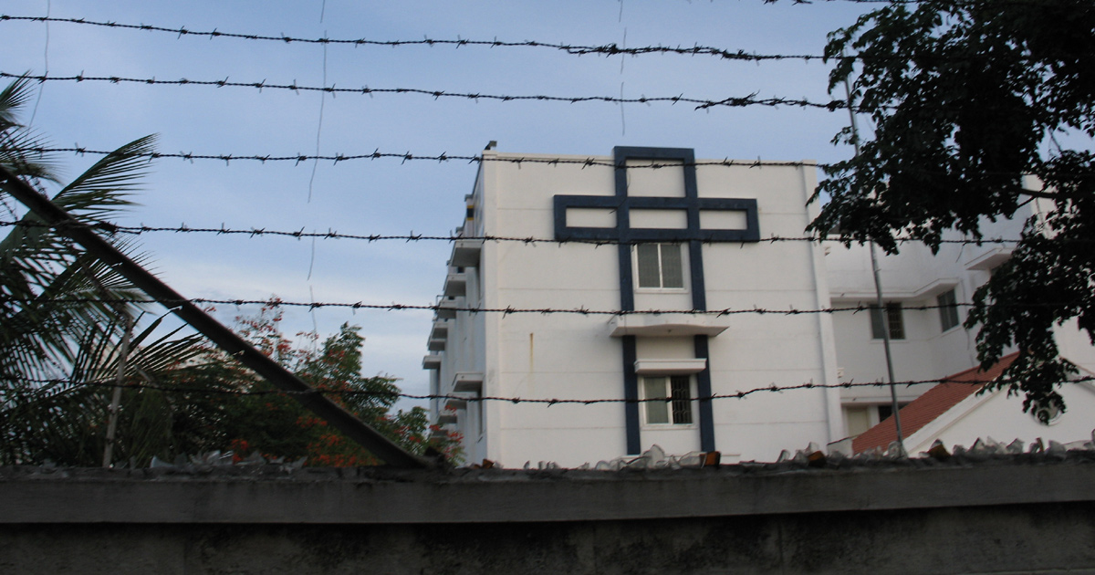 A church in India behind a protective fence with barbed wire.