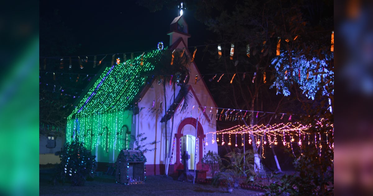 A small church shines in the night with colourful Christmas lights.