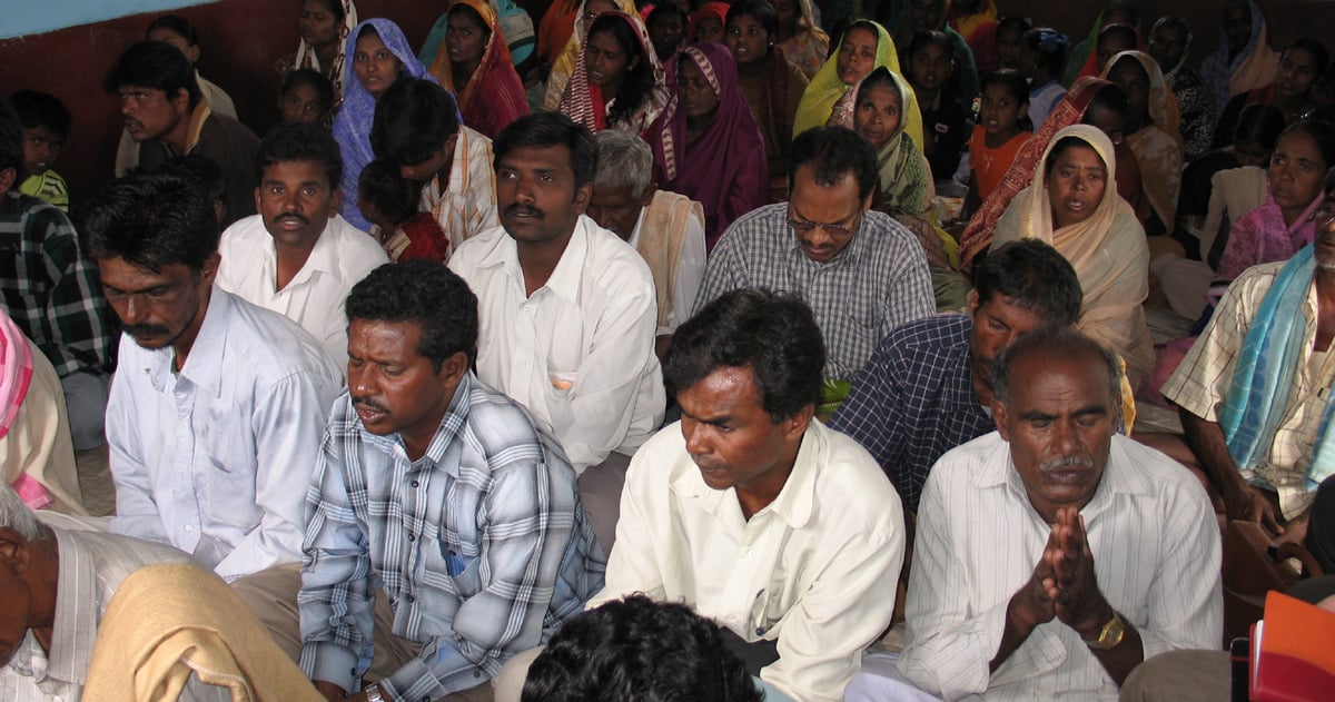 Several people are gathered in prayer.