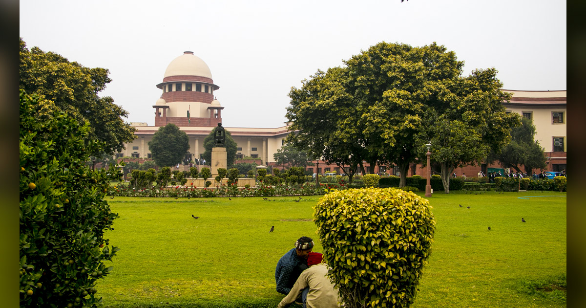The India Supreme Court building is surrounded by trees.