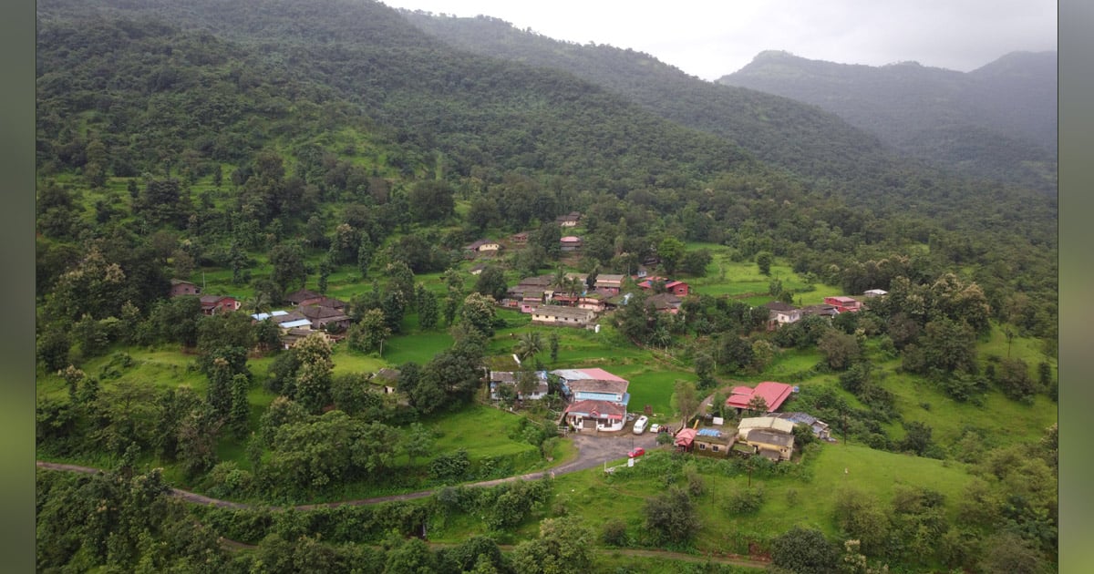Village homes are scattered across a forested hillside.