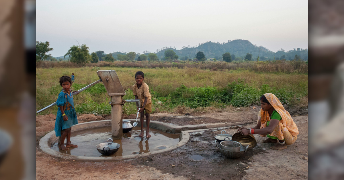 People are gathered at an outdoor water pump. People are gathered at an outdoor water pump.