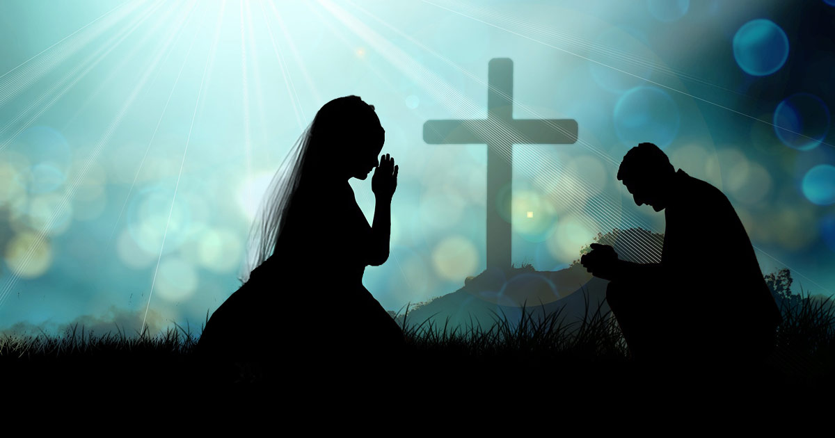 A man and a woman kneeling in prayer with the shadow of a cross behind them.