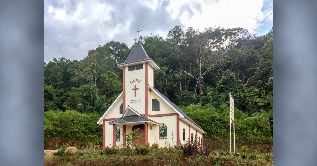 A picturesque church with a steeple is surrounded by trees.