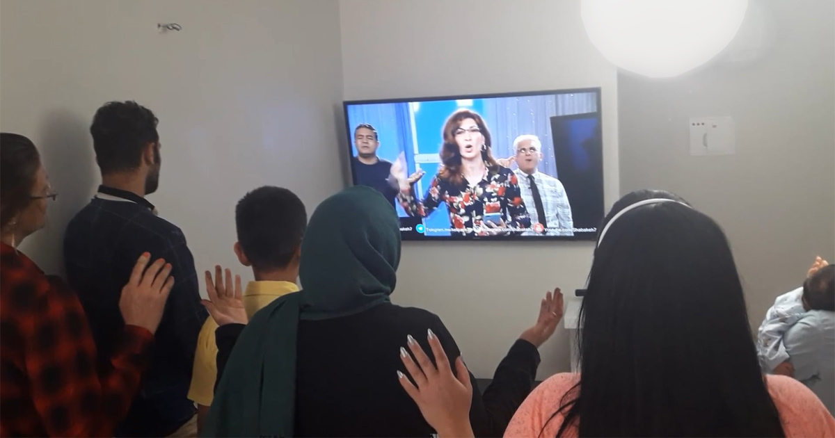 A house church is holding a service being led by a television program. A house church is holding a service being led by a television program.