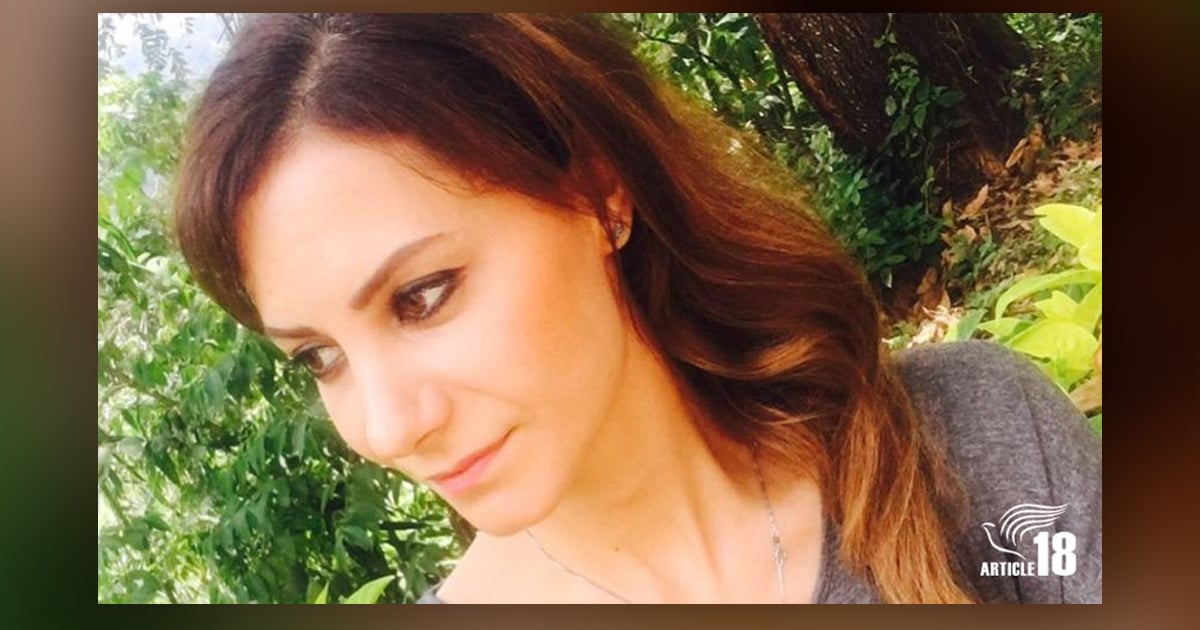 A smiling Laleh is outside, and the sun is shining on her face. A tree is in the background.