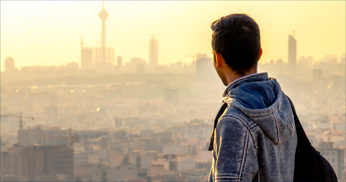 A man is is overlooking a hazy view of the city.