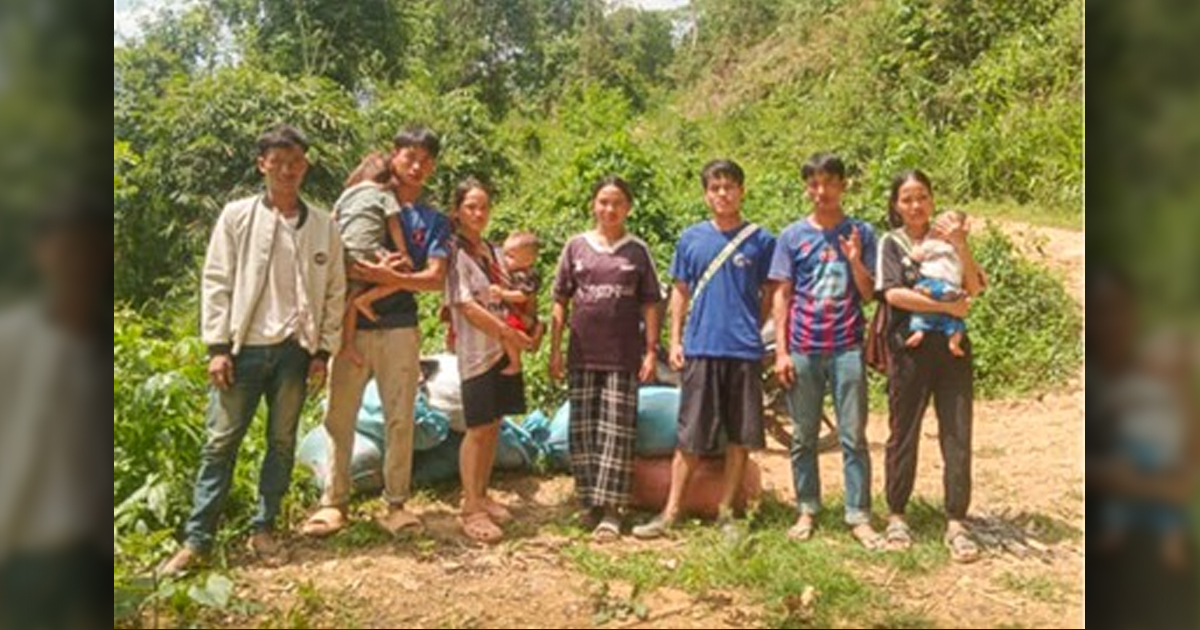 Seven adults and three small children are at the side of a road.