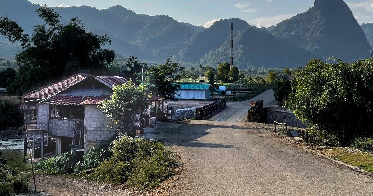 A large wooded area partially hides a village in the mountains of Laos.