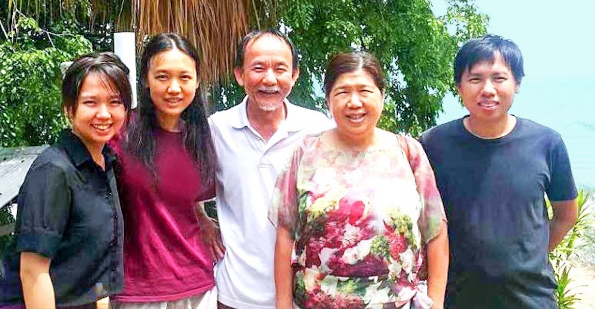 Raymond Koh is posing with his wife, two daughters, and son.