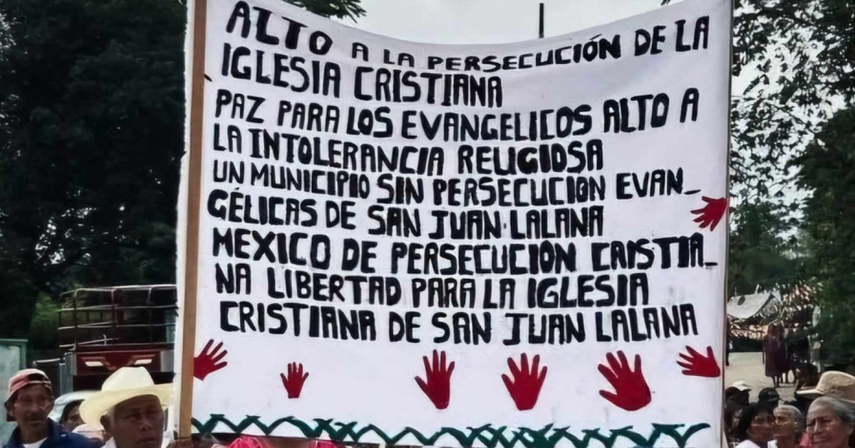 People are holding a sign at a protest. The sign when translated reads, "Stop the persecution of the Christian church. Peace for evangelicals also to religious intolerance. A municipality without Evangelical persecution of San Juan Lalana Mexico from Christian persecution. Freedom for the Christian church of San Juan Lalana."