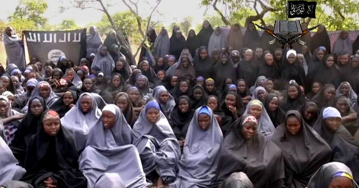 A large number of captive girls gathered in front of Boko Haram flags