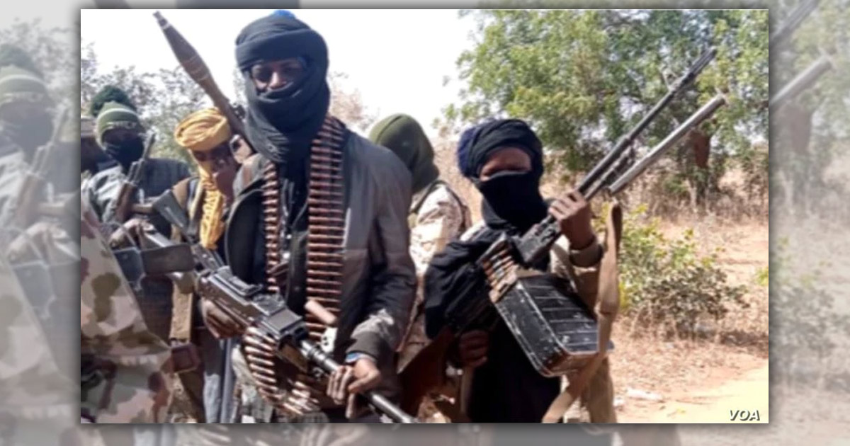 Several men are standing together with their faces covered, holding heavy artiliary.