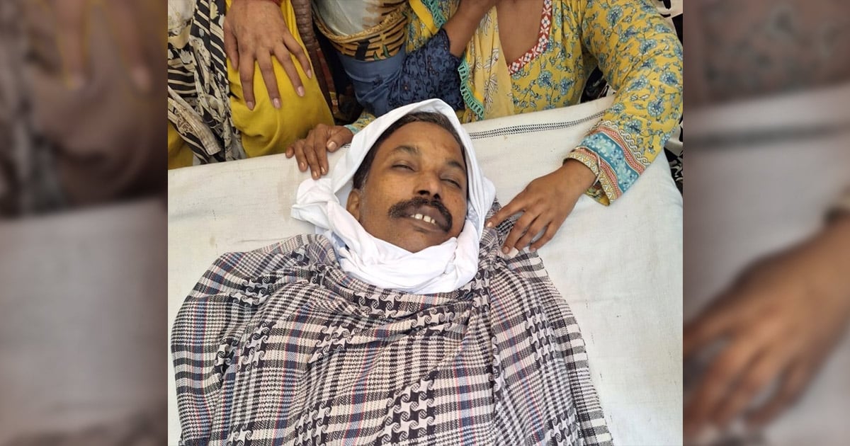 Afzal Masih is surrounded by mourners. One woman's hands are gently touching the wraps covering him.