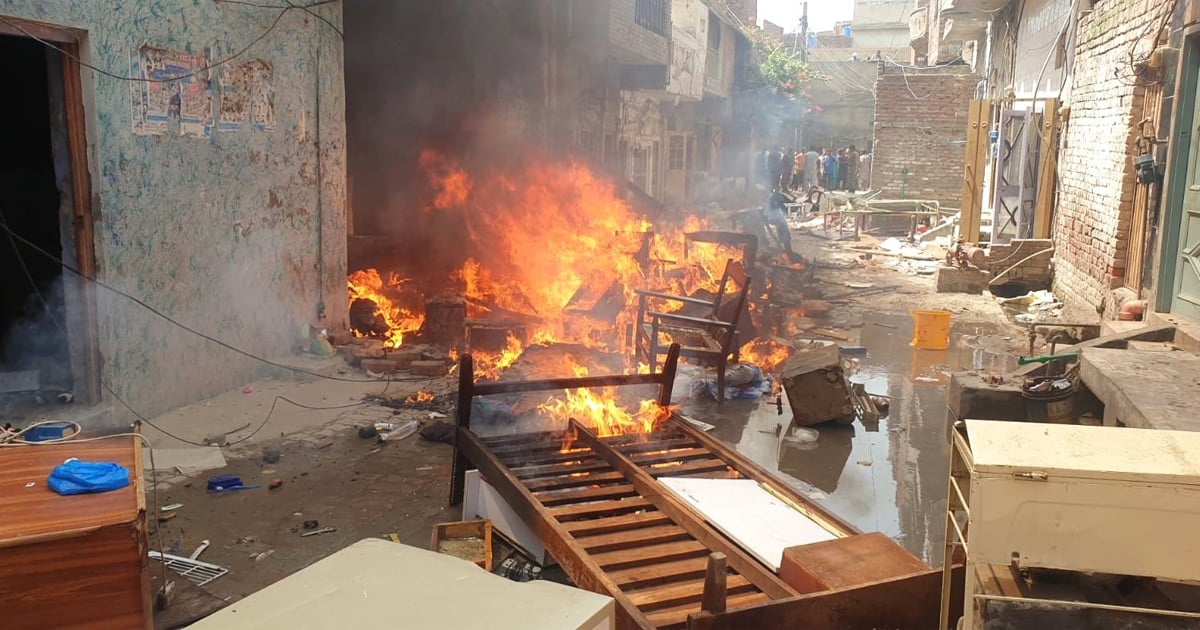 Furniture and possessions are strewn on a street. Some of them are burning.