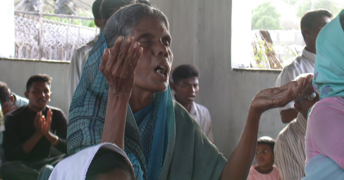 A woman is raising her hands in worship.