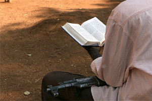 A Sudanese soldier is reading the Bible while holding a kalashnikov on his lap. - Photo: World Watch Monitor