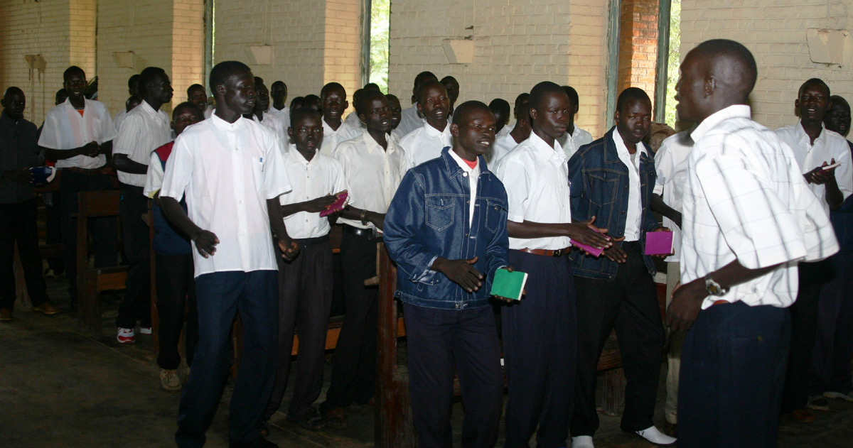 A group of men are standing together. They appear to be singing.