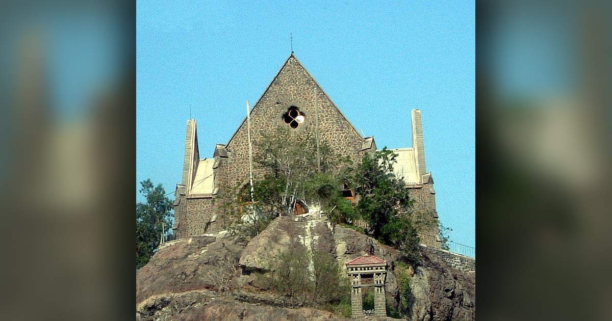 A church on a hill is surrounded by trees.