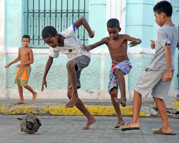 Boys are playing soccer in a street.