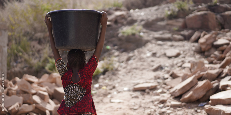 Young girl carrying a large bucket on her head