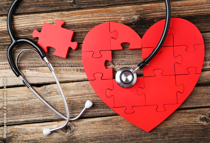 A red heart-shaped puzzle has one piece missing. A stethoscope is arranged over the puzzle.