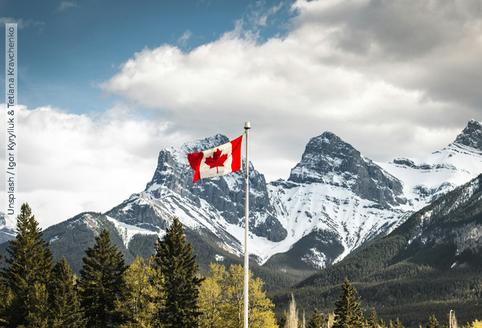 The snowy, rugged Rocky Mountains provide a stark background to a Canadian flag blowing in the breeze. The snowy, rugged Rocky Mountains provide a stark background to a Canadian flag blowing in the breeze.