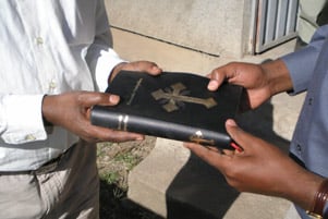 Two men are holding a Bible.