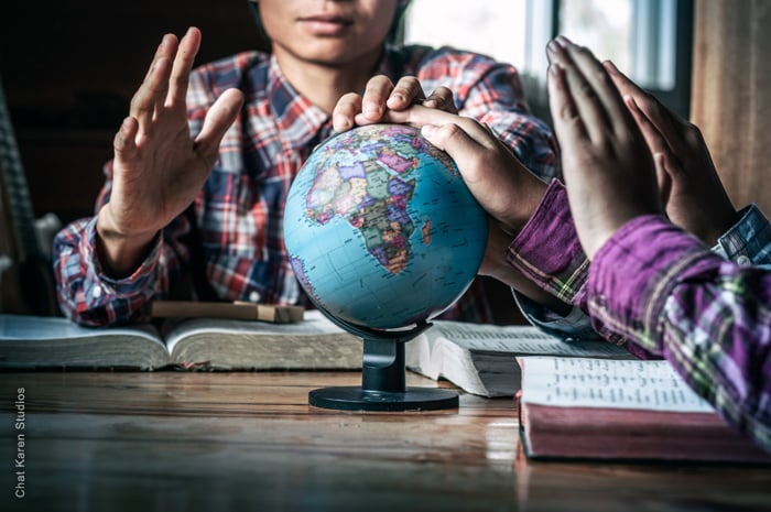 Two people praying over a globe