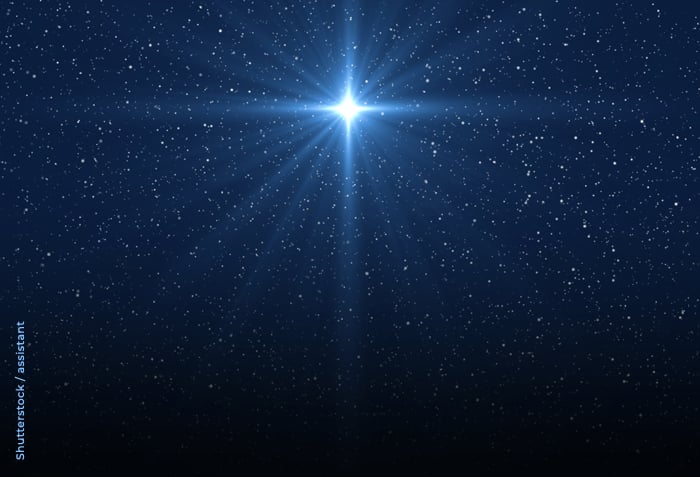 A brilliant star is bursting with rays of light in a sky full of tiny, distant stars.