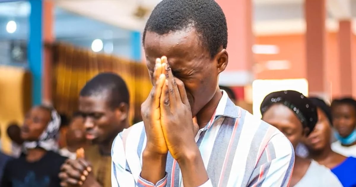 Greg Musselman is praying with a family. The parents' hands are covered with the clay from brick making. One of the two small children is looking up to the Daddy.